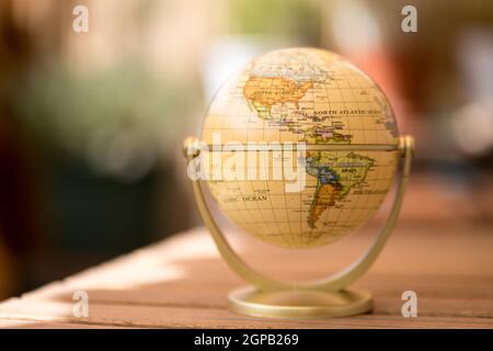 Pianificazione del viaggio successivo: globo in miniatura su un tavolo rustico Foto Stock