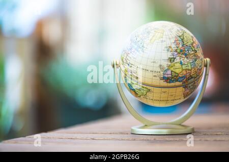 Pianificazione del viaggio successivo: globo in miniatura su un tavolo rustico Foto Stock