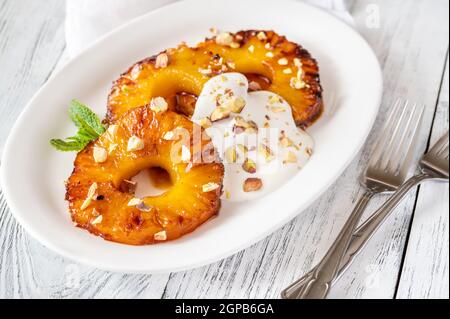 Ananas caramellato con panna montata e pistacchi sul piatto piastra Foto Stock