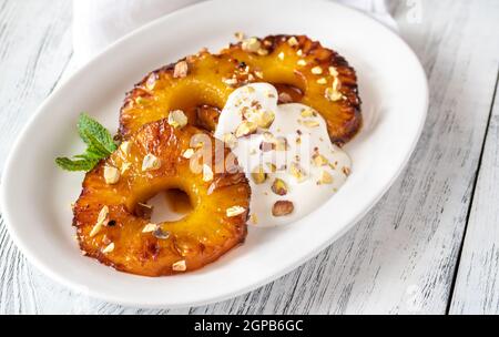 Ananas caramellato con panna montata e pistacchi sul piatto piastra Foto Stock