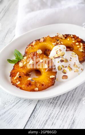 Ananas caramellato con panna montata e pistacchi sul piatto piastra Foto Stock