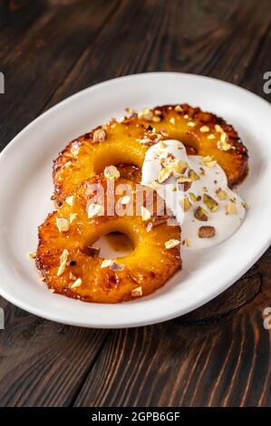 Ananas caramellato con panna montata e pistacchi sul piatto piastra Foto Stock