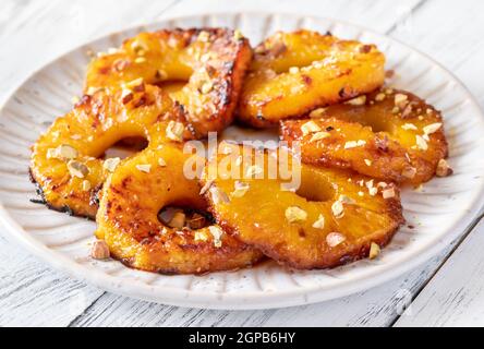 Ananas caramellato con panna montata e pistacchi sul piatto piastra Foto Stock