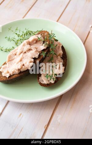 Spuntino di carne fatto in casa, patata di fegato di pollo con salato e olive su fette di pane scuro. Immagine verticale Foto Stock