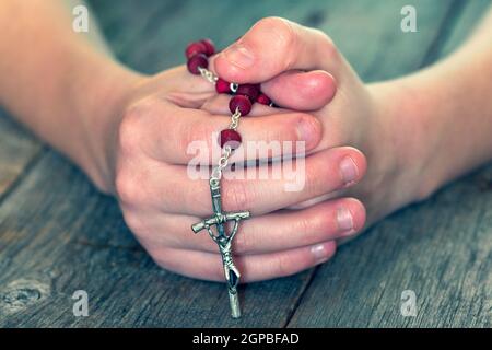 Childs mani Rosario cattolico. Bambino orante. DOF poco profondo. Foto Stock