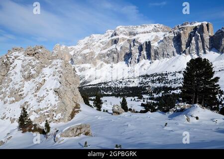 Il paesaggio delle Dolomiti di pittoresca ski run tra grandi massi in vista delle scogliere verticali cosparso con neve, girato in condizioni di intensa luce invernale Foto Stock