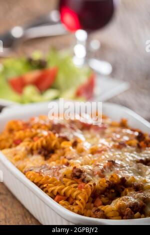 pasta gratinata con insalata su legno Foto Stock