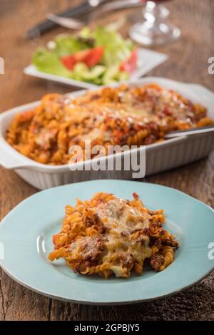 pasta gratinata con insalata su legno Foto Stock