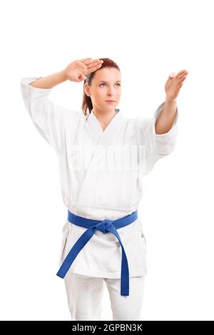 Ritratto di una bella giovane atleta di arti marziali in bianco kimono e cintura blu in una posizione di combattimento, isolato su sfondo bianco. Ma Foto Stock