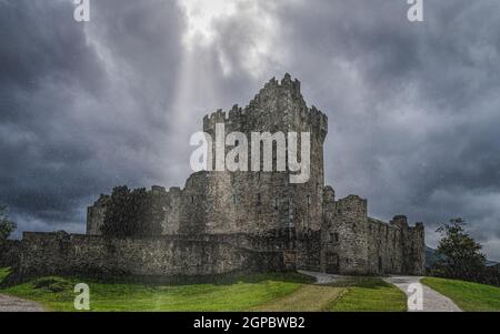 Il castello di Ross sotto la pioggia molto pesante e la tempesta di tuoni con le nuvole drammatiche, situato sulla riva di Lough Leane, Ring of Kerry, Killarney, Irlanda Foto Stock