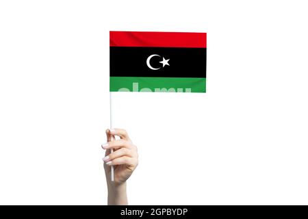 Bella mano femminile che tiene bandiera libica, isolato su sfondo bianco. Foto Stock