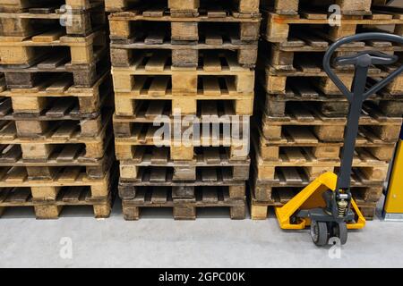 Transpallet manuale con pila di pallet in legno. Apparecchiature di magazzino. Trasporto di merci in stock.lifting equipment. Primo piano Foto Stock