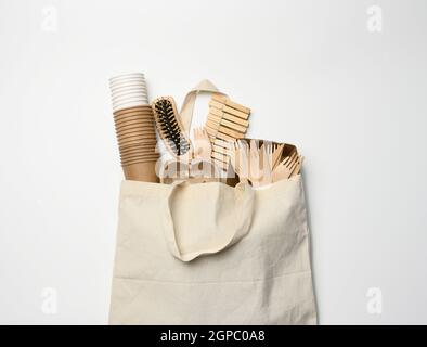 borsa in tessuto bianco e stoviglie monouso di carta marrone artigianale su sfondo bianco. Vista dall'alto, concetto di rifiuto della plastica, zero sprechi Foto Stock