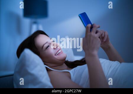 Insonnia Casa da sola utilizzando il telefono a tarda notte Foto Stock