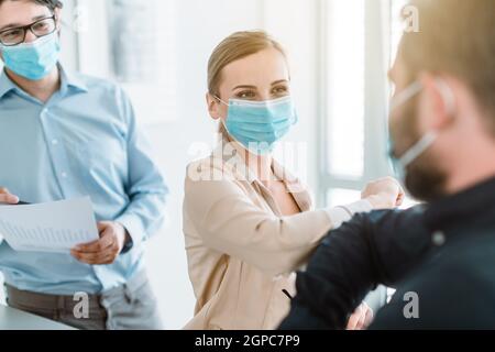 Uomini d'affari che fanno corona bump per salutarsi a vicenda in riunione di lavoro Foto Stock