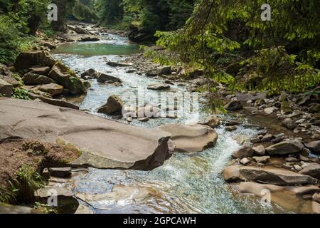 Piccolo fiume che scorre rapidamente e vividamente attraverso la sua valle rocciosa selvaggia Foto Stock