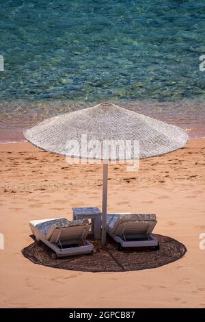 Spiaggia di sabbia di lusso con sedie da spiaggia e ombrellone bianco in resort tropicale nella costa del Mar Rosso in Egitto, Africa. Spiagge vuote durante la quarantena Foto Stock