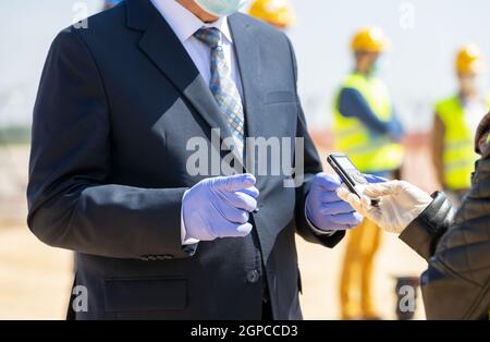 Giornalista femminile che fa l'intervista di mezzi con il politico o il businessperson durante Coronavirus COVID-19 malattia Foto Stock