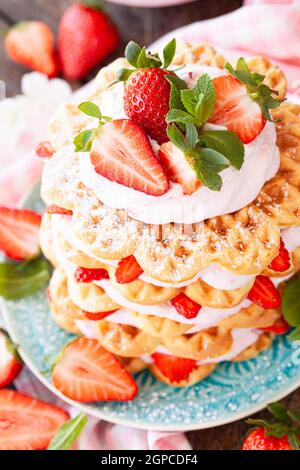 Waffle accatastati con panna montata e fragole fresche Foto Stock