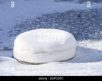 Flottante di impedimento di ghiaccio realizzato in polistirolo in un laghetto congelato Foto Stock