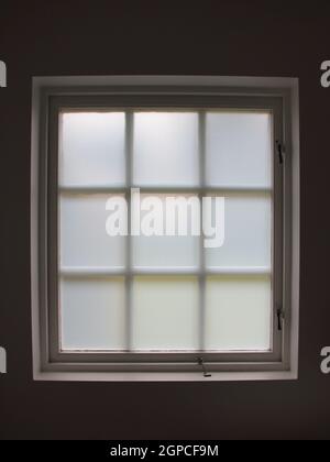 Una vecchia finestra del bagno colorata, simmetrica con un'apertura con chiusura a scatto. È retroilluminato. Foto Stock