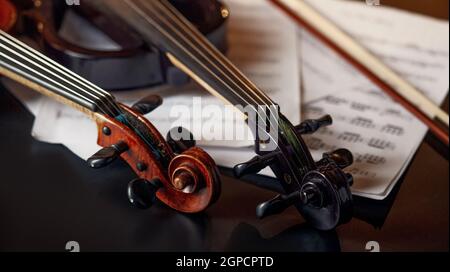 Violino retrò e viola elettrico moderno, primo piano, nessuno. Due strumenti musicali classici a corda, taccuino musicale sullo sfondo Foto Stock