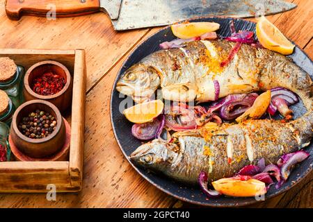 Due trote alla griglia con limone e cipolla sul piatto Foto Stock