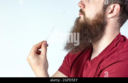 Test autodiagnostico del coronavirus a casa. Il giovane esegue un test rapido a casa con il covid-19. Test con tampone di cotone nel naso del giovane su backgroun bianco Foto Stock