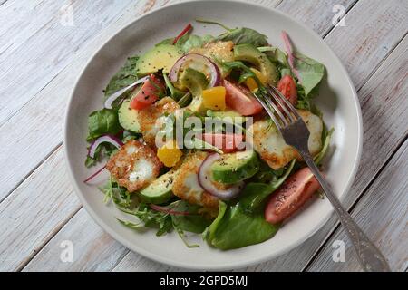 Insalata di formaggio halloumi mediorientale alla griglia con avocado, arance, pomodori ciliegini, cipolla rossa, foglie di barbabietola di rucola. . Foto Stock