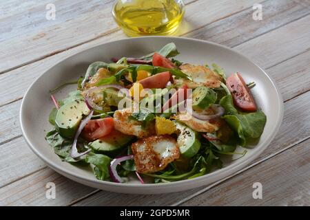 Insalata di formaggio halloumi mediorientale alla griglia con avocado, arance, pomodori ciliegini, cipolla rossa, foglie di barbabietola di rucola. . Foto Stock