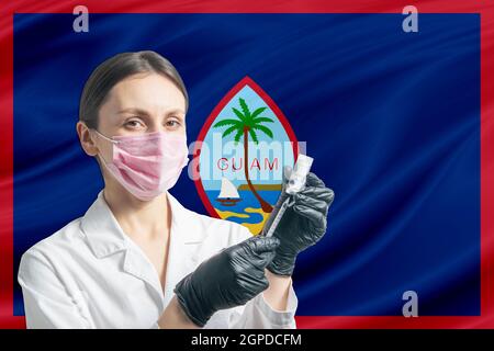 Medico di ragazza prepara la vaccinazione sullo sfondo della bandiera di Guam. Concetto di vaccinazione Guam. Foto Stock