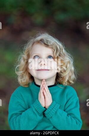 Bellissimo bambino orante con le sue mani toguether Foto Stock