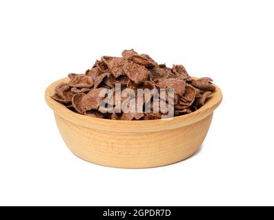 cornflakes di cioccolato in piastra di legno isolata su sfondo bianco, colazione secca del mattino Foto Stock