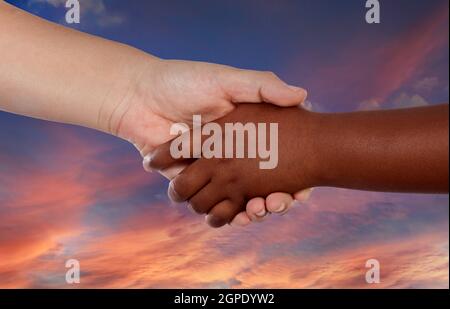 Agitare tra due mani con colori diversi su un incredibile cielo di sfondo Foto Stock
