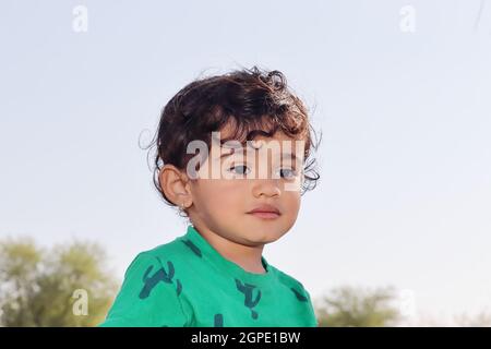 Ritratto di un piccolo bambino carino di origine indiana Rajasthani famiglia contadina indù con primo piano volto del bambino nella foto con sfondo sfocato di Foto Stock