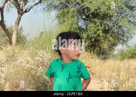 Ritratto da vicino di ragazzino di origine indiana che coltiva la famiglia in piedi fuori dalla foresta e guardando via Foto Stock