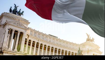 La bandiera italiana sventolando nel vento con Vittoriano a Roma sullo sfondo. Viaggi e destinazioni turistiche. Arte e architettura. Ita famosa in tutto il mondo Foto Stock