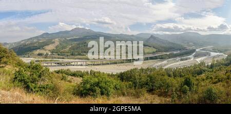 Paesaggio della valle del fiume Pennine Taro con lungo viadotto della Cisa autostrada che attraversa il fiume e la ferrovia nelle vicinanze, girato in luce brillante a fine estate vicino Foto Stock