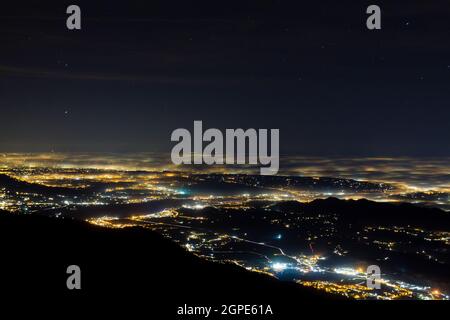 Plain illumina parzialmente coperta dalla nebbia, luci soffuse. Monte Grappa, paesaggio italiano Foto Stock