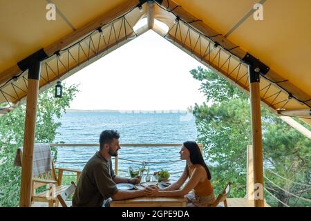 Giovane coppia romantica cena al mare durante il riposo in tenda glamping Foto Stock