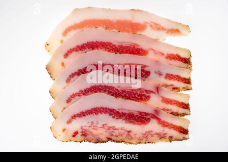 Guanciale italiano, fettine di guancia di maiale stagionata a secco isolate su bianco nella vista dall'alto Foto Stock