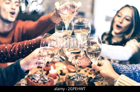Gruppo di amici che festeggia il Natale con degustazione di champagne a casa cena - concetto di vacanza invernale con i giovani che si divertono e si divertono Foto Stock