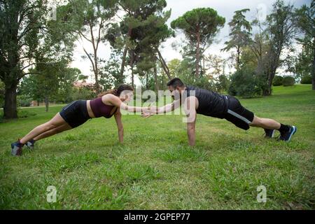 felice giovane uomo e donna caucasica coppia praticare push-up e high-fives all'aperto Foto Stock