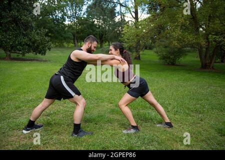 giovane uomo caucasico e donna coppia praticare la forza esercizio all'aperto Foto Stock