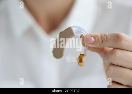 La donna tiene gli apparecchi acustici a portata di mano Foto Stock