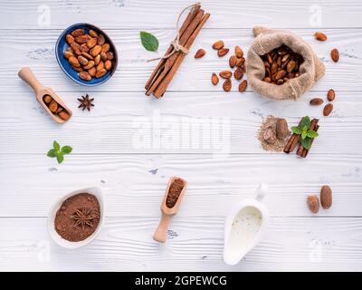 Cacao in polvere e chicchi di cacao su sfondo di legno. Cioccolato fondente pezzi frantumato e erbe aromatiche . Foto Stock