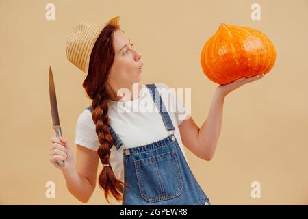 Donna sorpresa con le dimensioni di una zucca grande su con un coltello. Foto Stock