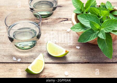 Ingredienti per rendere mojito con foglie di menta, calce,limone e vodka su sfondo rustico. Foto Stock