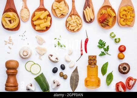 Il cibo italiano concetto .vari tipi di pasta in cucchiai di legno con ingredienti basilico dolce ,il pomodoro , Aglio , Prezzemolo , alloro ,pepe ,champignon e Foto Stock