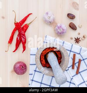Assortimento di spezie e di ingredienti pasta del popolare tailandese cibo curry rosso con mortaio impostato sul tavolo di legno. Foto Stock